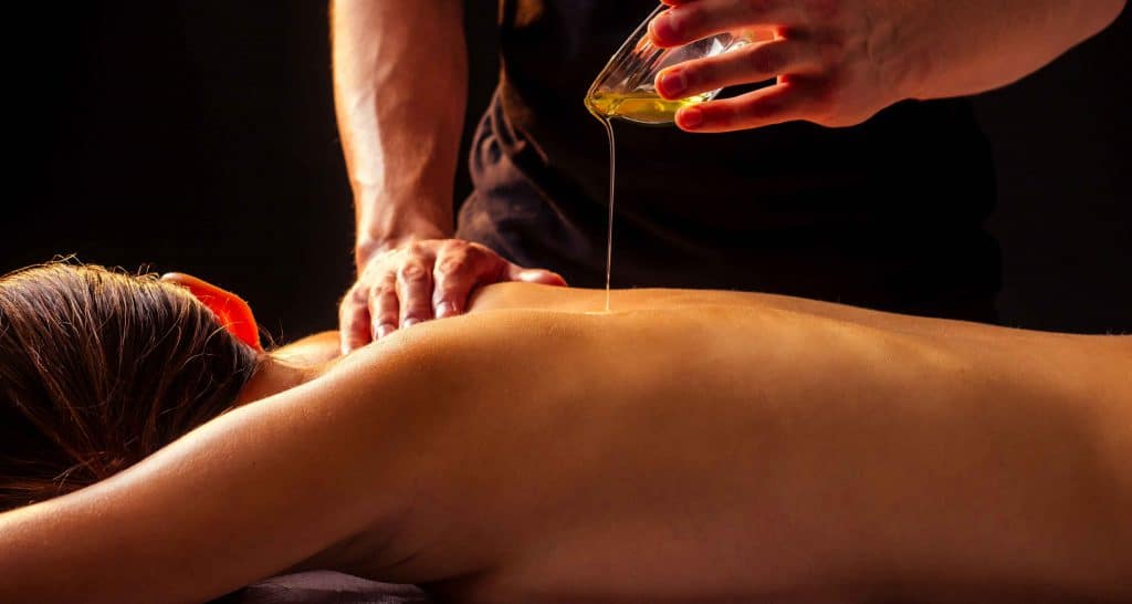 Abhyanga ayurvedische oliemassage met warme olie die uit een hand stroomt, voor ontspanning, balans en stressvermindering.